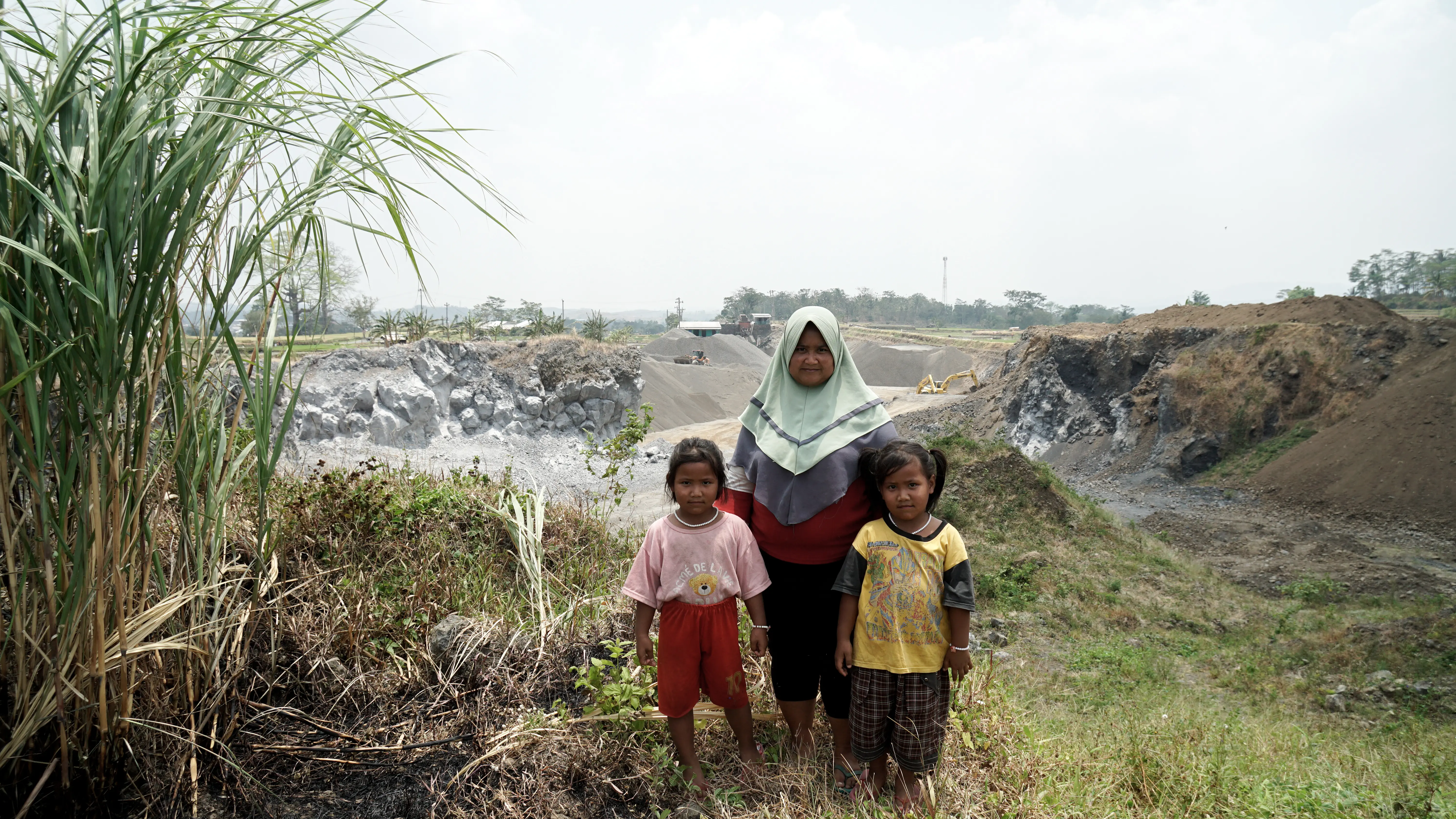 Ibu Purwati dan 2 anak kembarnya, Nabila dan Nadila, dengan latar belakang tanah rumah mereka yang lama